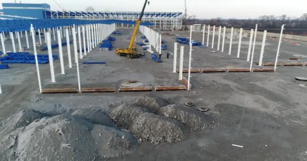 Um grande guindaste de construção, pessoas que trabalham no canteiro de obras de uma fábrica moderna. O guindaste monta a estrutura metálica — Vídeo de Stock