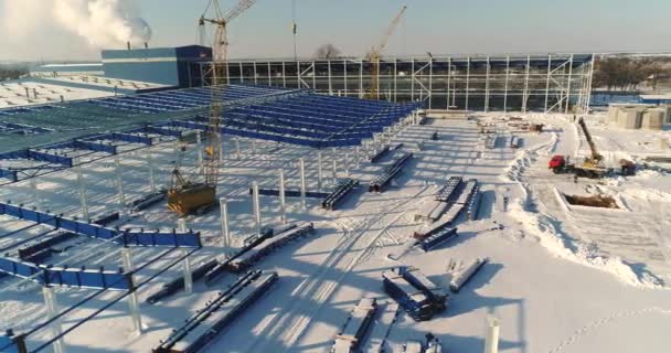 Construção de uma fábrica ou planta moderna, área industrial no inverno, vista panorâmica do ar. Planta moderna no campo coberto de neve, a estrutura de aço estrutural de um novo edifício comercial — Vídeo de Stock