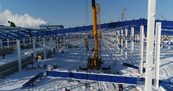 Werk van de kraan op de bouwplaats, de kraan verhoogt de ijzeren balk. Werknemers op de bouwplaats, mensen die werkzaam zijn op de hoogte van de bouwplaats. Gevaarlijk werk. — Stockvideo