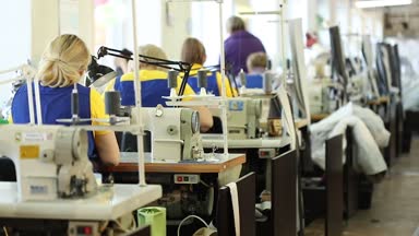 Çalışan bir dikiş makinesi, endüstriyel boyutu tekstil fabrikası, işçilerin üretim hattı, sanayi iç, iğne dikiş makinesi, sığ derinlik-in tarla, kadın