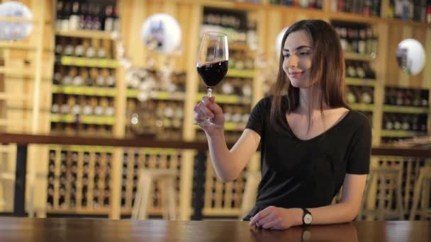 Mulher tomando um copo de vinho tinto, Uma menina com um copo de vinho tinto, uma jovem menina bonita está bebendo vinho tinto em um restaurante — Vídeo de Stock