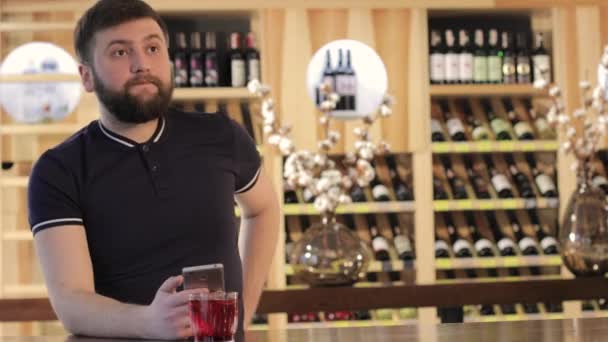 Человек ipster пить красный напиток в ресторане или кафе, молодой человек, использующий смартфон во время питья красного коктейля — стоковое видео
