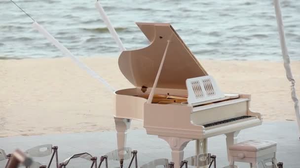 A háttérben a tenger, fehér zongora állt a parton, esküvő a tengerparton, a zongora koncepció — Stock videók