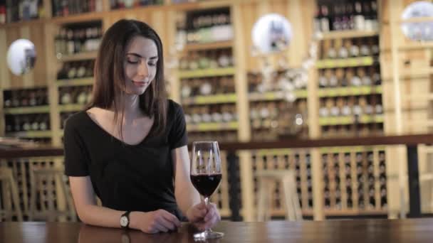 Γυναίκα που έχει ένα ποτήρι κόκκινο κρασί, ένα κορίτσι με ένα ποτήρι κόκκινο κρασί, μια νεαρή όμορφη κοπέλα πόσιμο κόκκινο κρασί σε ένα εστιατόριο — Αρχείο Βίντεο