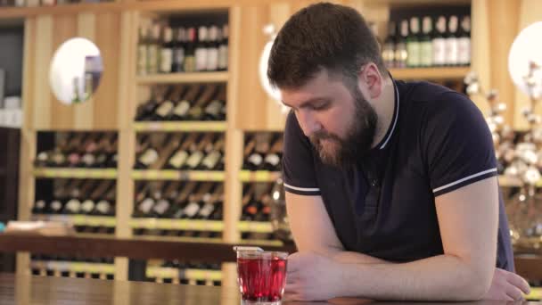 Hombre ipster bebiendo una bebida roja en un restaurante o cafetería, un joven usando un teléfono inteligente mientras bebe un cóctel rojo — Vídeo de stock