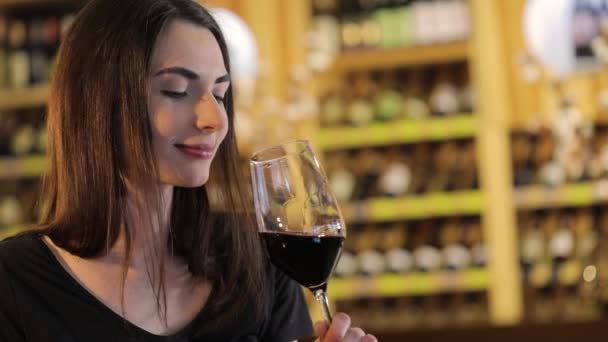 Mujer tomando una copa de vino tinto, Una chica con una copa de vino tinto, una joven hermosa chica está bebiendo vino tinto en un restaurante — Vídeos de Stock