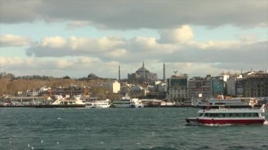 Büyük bir caminin arka planında Türk bayrakları olan bir tekne. Hindi, İstanbul. Boğaz 'da turist tekneleri