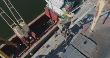 İskele vinçleri kuru bir kargo gemisini yüklüyor. Büyük port vinçlerinin işi