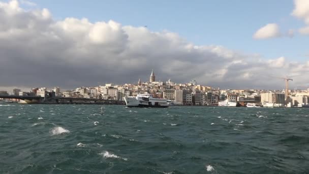 Langsom film av Galata Tower, i forgrunns gledesbåter med turister og måker. Lystbåter i bakgrunnen av Galata Tower, vindstille vær – stockvideo