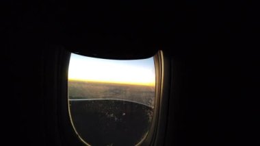 Güneşin doğuşu bir uçakla pencereye doğru. Uçak penceresinden gün batımı