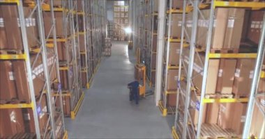 Depoda bir forklift, büyük bir depoda bir adam işi halleder.