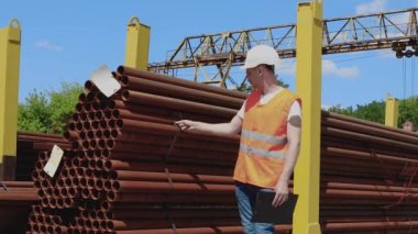 Depo çalışanı metalin envanterini çıkarıyor. Yönetici ürün sayısını sayar