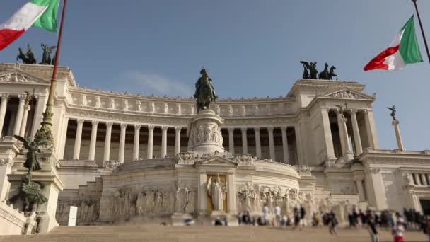 Turistas cerca del Monumento a Víctor Manuel II. Italia banderas cerca del monumento a Victor Emmanuel revoloteando en el viento. Plaza de Venecia en Roma — Vídeo de stock