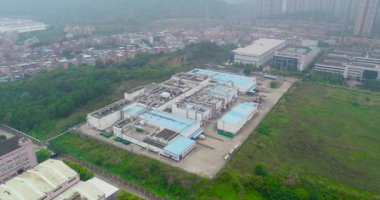 Arka planda küçük Çin fabrikalarının, dağların ve yerleşim alanlarının üzerinde uçuş