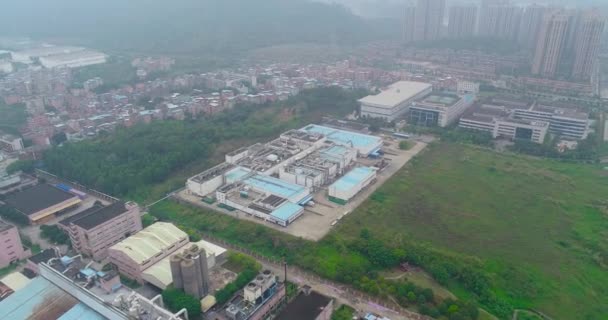 Sobrevoo de pequenas fábricas chinesas, montanhas e área residencial no fundo — Vídeo de Stock