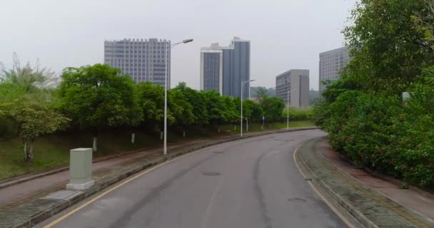 Volando por el camino vacío y despegando por encima de los árboles, con vistas a la ciudad china — Vídeo de stock