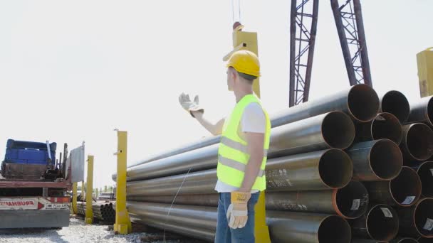 El trabajador da instrucciones a la grúa pórtico, el control de movimiento de la grúa pórtico con la ayuda de gestos, el hombre trabaja en el almacén — Vídeo de stock