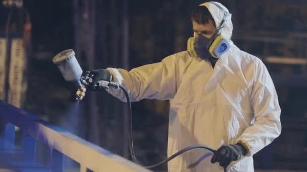 A man in a protective suit paints a large part, a spray gun, painting a large metal part — Stock Video