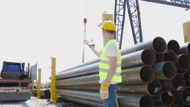 El trabajador da instrucciones a la grúa pórtico, el control de movimiento de la grúa pórtico con la ayuda de gestos, el hombre trabaja en el almacén — Vídeo de stock