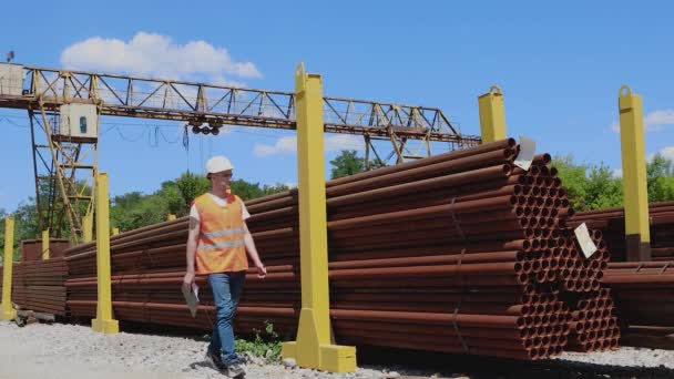 Um trabalhador de armazém faz anotações no caderno. O trabalhador do armazém faz um inventário do metal. O gerente conta o número de produtos — Vídeo de Stock