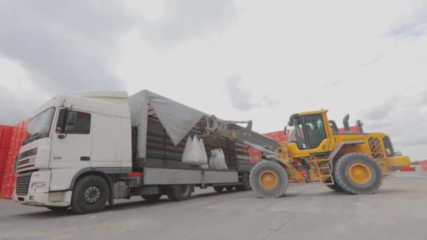 En bulldozer lastar av väskor i en lastbil. Lasta av varor från lastbilen. Bulldozer lossar gods från en bil — Stockvideo