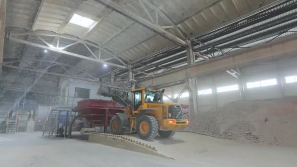 Een bulldozer laadt zand op een maalmolen in een kogelmolen. Belastingsmateriaal op de transportband — Stockvideo