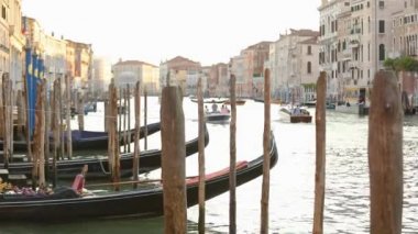 İskele, iskelenin yanındaki gondollar. Arka arkaya birkaç gondol. Büyük kanalın güzel çerçevesi