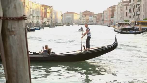 Gondel met toeristen in een groot kanaal in Venetië. Prachtig groot grachtenpand. Gondelaar rijdt toeristen Venetië, Italië. Romantische plek Venetië — Stockvideo