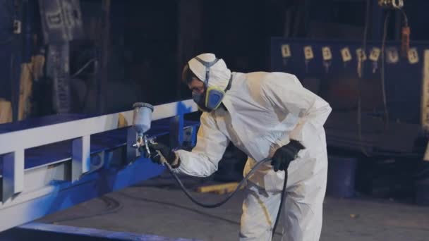 Um homem de fato protector pinta uma grande parte, uma pistola de pulverização, pintando uma grande parte de metal — Vídeo de Stock