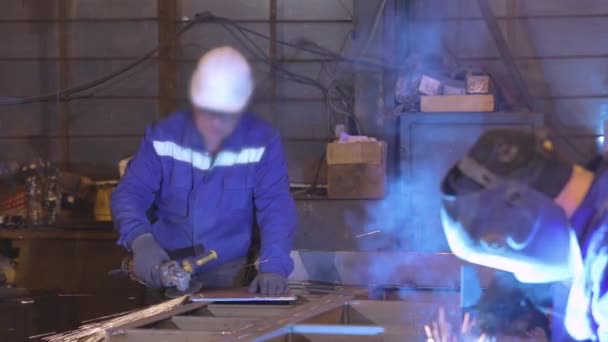 Az ember darálóként dolgozik egy műhelyben, fényes szikrák egy darálóból. — Stock videók