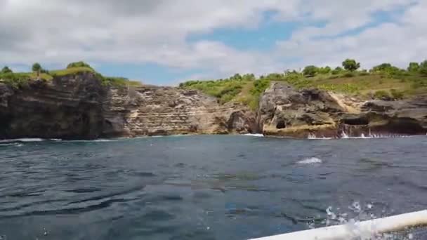 La barca galleggia oltre le rocce vive, belle rocce sulla riva a Bali — Video Stock