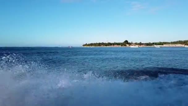 Člun rychle plave podél vln na Bali a kolem se valí spousta šplouchání. Motorový člun pluje podél vln, více spreje po stranách. — Stock video