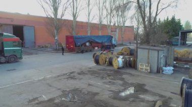 Kablolu babunların üzerinde gerilmek, açık gökyüzünün altında kabloyla büyük bobinler. Kablo fabrikasının yanındaki depo.