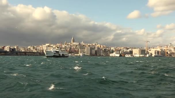 観光客やカモメと前景の喜びのボートで、ガラタ塔のショット。ガラタ塔、風の強い天候の背景にある喜びのボート — ストック動画