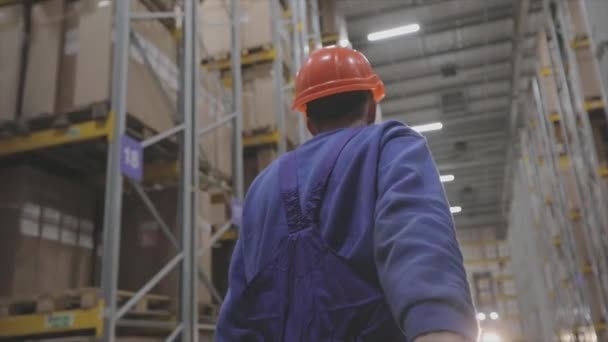 Een man in een fabriek, een man loopt in een fabriek, een bouwer in een helm — Stockvideo