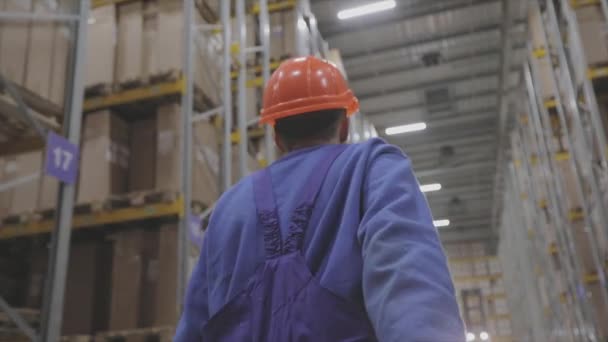 Un hombre en una fábrica, un hombre camina en una fábrica, un constructor en un casco — Vídeos de Stock