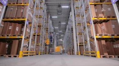 Bir işçi ambardaki modern bir forkliftle yük taşır. Büyük bir depoda çalışıyorum.