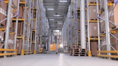 Erkekler bir depoda forkliftle kutu taşır depoda aktif bir iş, büyük modern bir depo. Bir üretim deposundaki makineler.