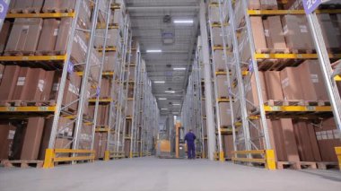 Depoda bir forklift, büyük bir depoda bir adam işi halleder.