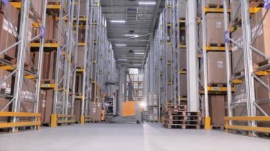 Erkekler bir depoda forkliftle kutu taşıyorlar. Büyük, modern bir depo. Bir üretim deposundaki makineler.