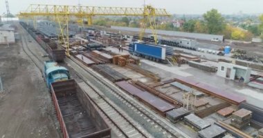 Açık alanda büyük bir metal ürün deposu, metal bir zeminde sarı bir kanat vinci.