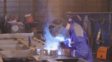 Ağır çekimde çalışan bir fabrika işçisinin metal parçaları kaynak işlemi.