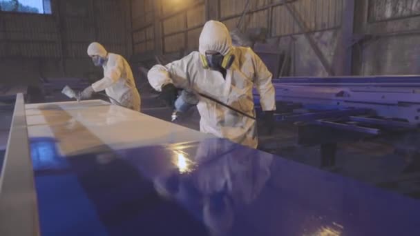 Los hombres pintan un gran detalle en azul, Pintura en la fábrica. Pintura de piezas grandes — Vídeos de Stock