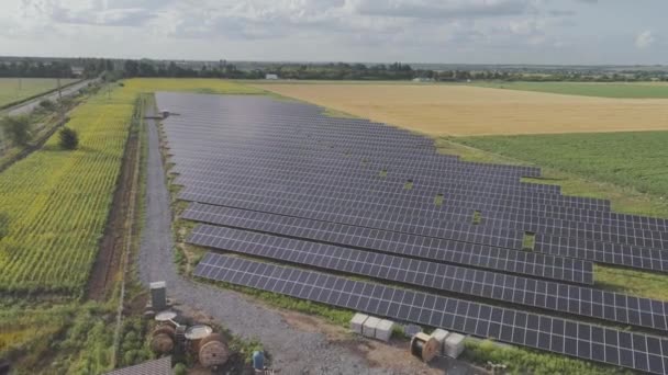 Flyger över ett fält av solpaneler, runt gröna fält. Förnybar energi, solpaneler — Stockvideo