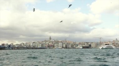 Arka planda, Boğaz boyunca uzanan büyük ve modern bir yat Galata Kulesi 'dir. Koyu altın boynuz