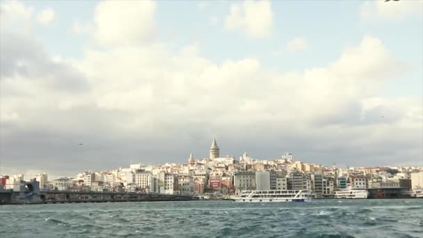 Galata Kulesi, ön planda turistler ve martılarla dolu eğlence tekneleri. Galata Kulesi 'nin arka planında tekneler, rüzgarlı hava — Stok video