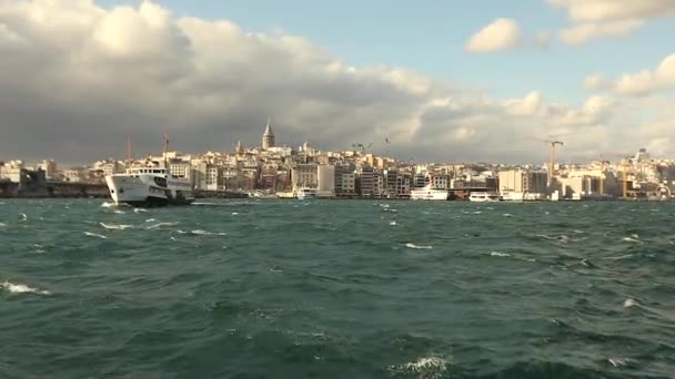 観光客やカモメと前景の喜びのボートで、ガラタ塔のショット。ガラタ塔、風の強い天候の背景にある喜びのボート — ストック動画