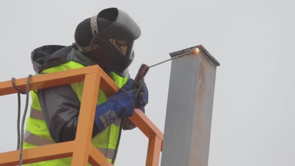 Un soldador trabaja en un primer plano del sitio de construcción, un soldador ensambla una estructura metálica — Vídeos de Stock