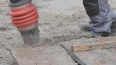 İnşaat alanında çalışan işçiler, rammer 'ı dolduran işçiler. Tamping toprağı
