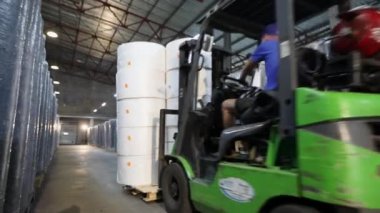 Sentetik malzeme deposunda bir forklift. Bir forklift dolgu yastığı sıralarının arasına girer. Bir forklift depoda mal taşır.